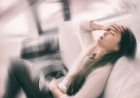 woman-holding-head-on-couch-migraine